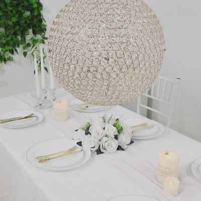 Gold crystal globe chandelier pendant hanging above a decorative table setting.