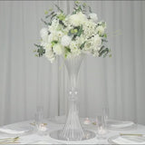 Clear ribbed acrylic trumpet vase with white floral arrangement centerpiece.