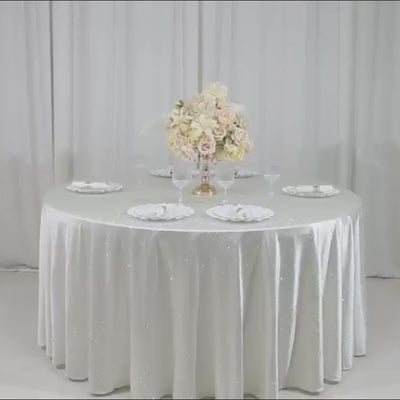 Pearl white round tablecloth with rhinestone accents on a dining table.