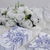 White napkins with blue French toile floral pattern on a table setting.