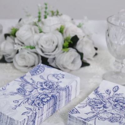 White napkins with blue French toile floral pattern on a table setting.
