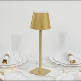 Gold metal cordless LED table lamp with adjustable height and ribbed shade.