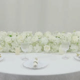 White silk flower table runner with roses and hydrangeas for wedding decor.