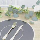 Black round disposable placemat with gold rim on a table setting.