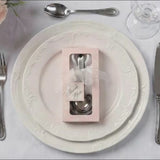 Engraved silver heart measuring spoons in a gift box on a white plate.
