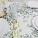 White plastic tablecloth with sage green French toile pattern on a dining table.