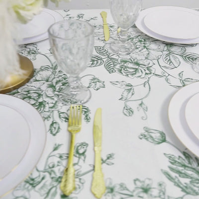 White plastic tablecloth with sage green French toile pattern on a dining table.