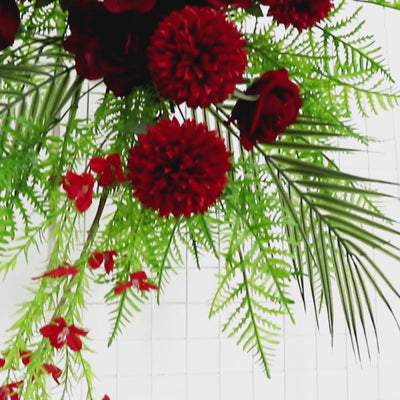 Burgundy rose and chrysanthemum floral swag with greenery and palm leaves.