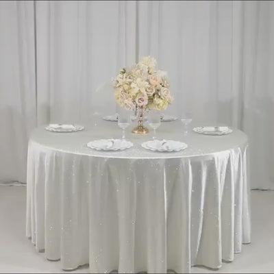 Pearl white round tablecloth with rhinestone accents on a dining table.