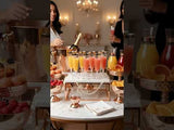 Elegant cocktail party setup with colorful drinks and fresh fruit displays.