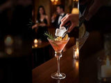 Hand garnishing a cocktail with a toasted marshmallow and rosemary sprig.