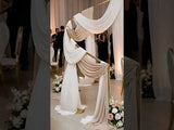 Elegant wedding backdrop with draped fabric and floral arrangements.