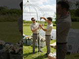 Two men assembling a wedding arch in an outdoor setting.