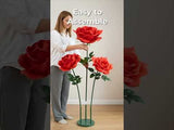 Woman assembling large decorative roses in a home setting.