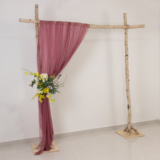Rustic wedding backdrop with draped fabric and floral arrangement.
