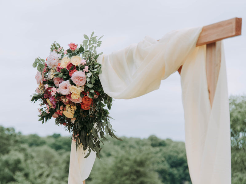 Wedding arch draped with ivory fabric and a flower arrangement