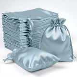 Stack of light blue satin drawstring bags on a white background.