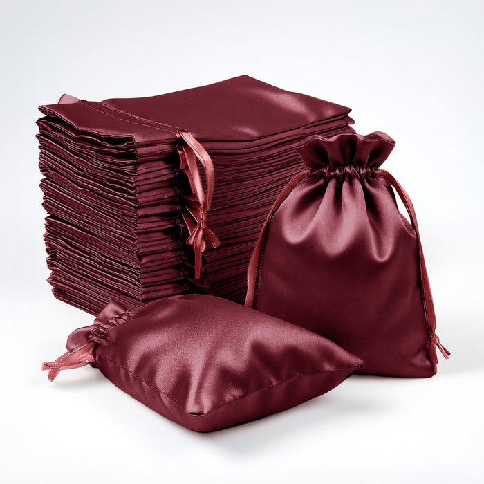 Burgundy satin drawstring bags and fabric squares stacked on a white background