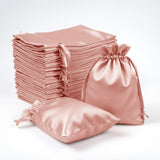 Stack of pink satin bags and pouches on a white background.