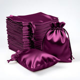 Stack of purple satin drawstring bags on white background