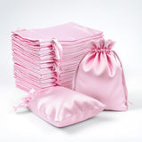 Pink satin bags and pouches stacked together on a white background