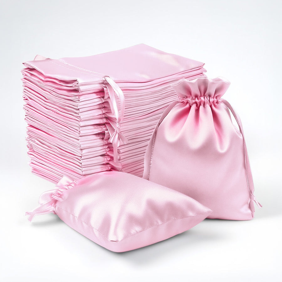 Pink satin bags and pouches stacked together on a white background