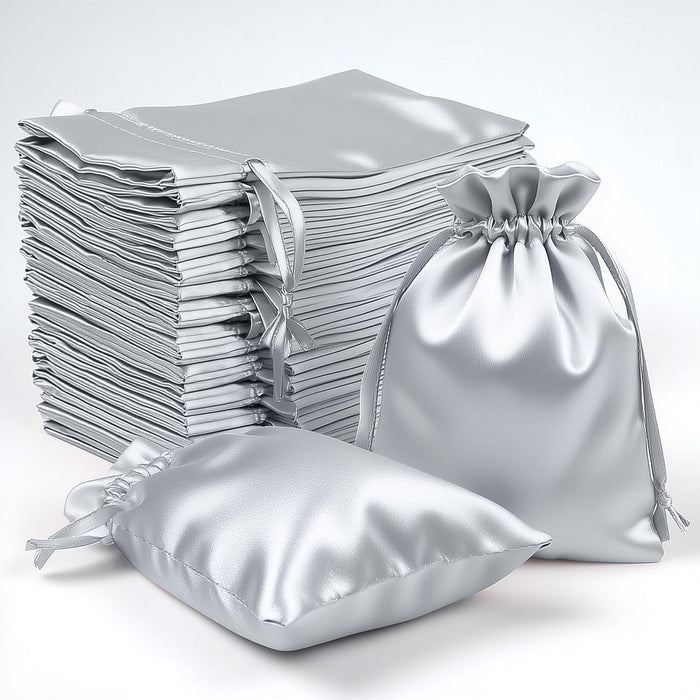 Silver satin drawstring bags stacked and arranged on a white backdrop.