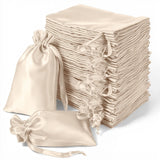 Stack of cream satin drawstring bags on a white background.