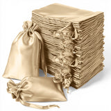 Stack of elegant satin gift bags in beige, with tied closures for special occasions.