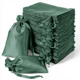 Stack of green satin drawstring bags on a white background.