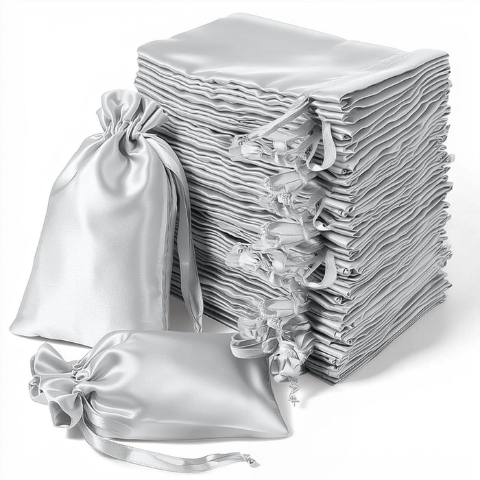 Stack of elegant silver satin drawstring bags on a white background