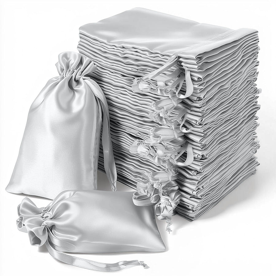 Stack of elegant silver satin drawstring bags on a white background