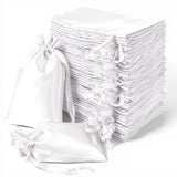 White satin drawstring bags stacked in a neat pile.