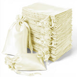 Stack of elegant cream satin gift bags with drawstring closures