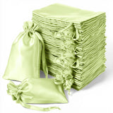 Stack of light green satin drawstring bags on a white background.