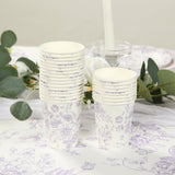 Stack of floral-patterned paper cups on a table with greenery.