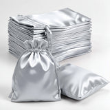 Silver satin drawstring bags on a white background