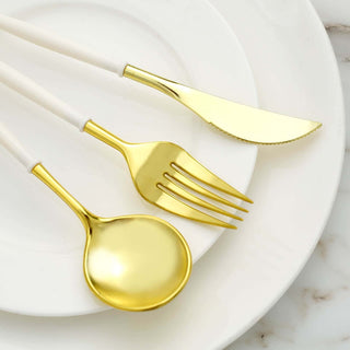 Gold cutlery set on white plates, featuring a spoon, fork, and knife.