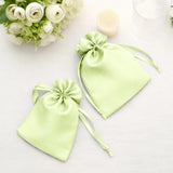 Green satin drawstring gift bags on a soft surface.