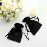 Two elegant black satin drawstring bags on a soft white surface.