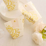 Gold rose thank you favor boxes on a table with plates and flowers.