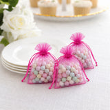 Pink organza candy gift bags with pastel pastel sweets on a white table