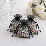 Black organza gift bags filled with pastel candy beads on white table