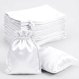 White satin drawstring bags stacked and one bag in the foreground.