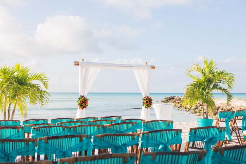 Beach wedding ceremony setup with white drapery arch