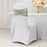 Elegant white chair cover with green velvet bow at a decorated table.