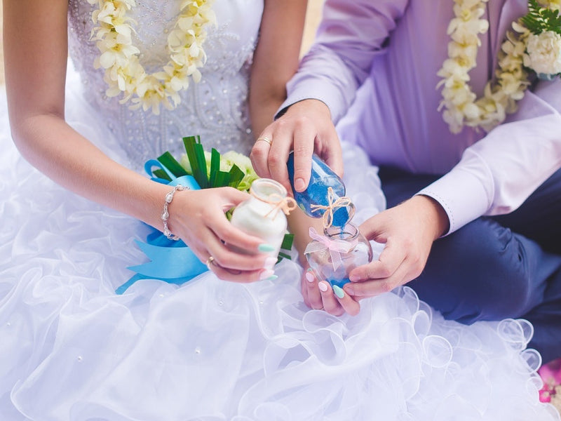 Bride and groom holding small decorated bottles