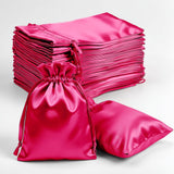 Pink satin drawstring bags and pillows on a white background
