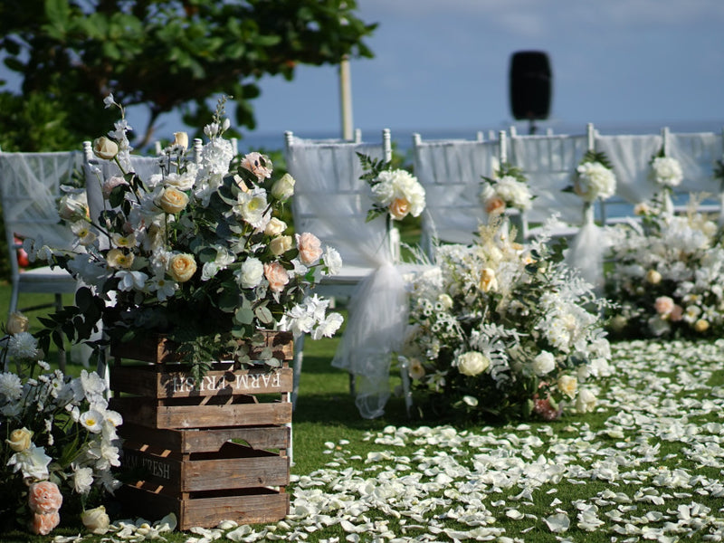 White floral wedding ceremony setup with petal-strewn lawn