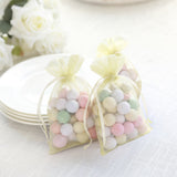 Pastel candy-filled bags tied with yellow ribbons on a table.